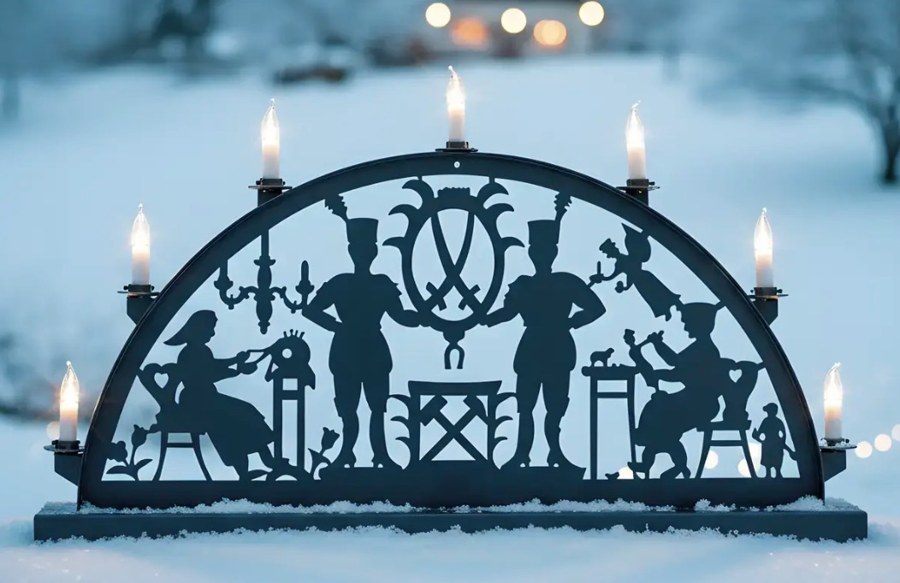 Beleuchteter Schwibbogen mit Bergmannsmotiven im Schnee